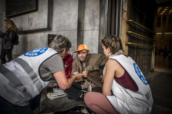 Twee vrijwilligers helpen een patiënt tijdens een wekelijkse ronde van de Medibus door de Brusselse wijken.
