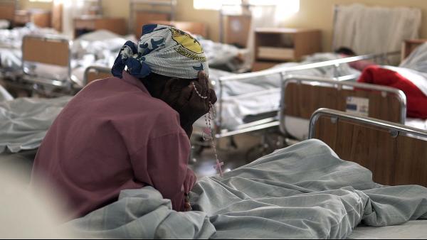 Femme assise sur son lit d'hôpital se tenant le visage entre les mains