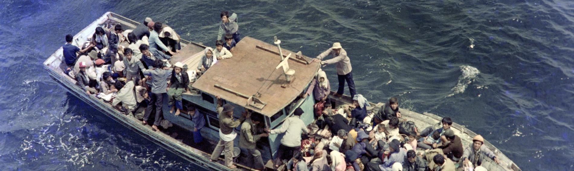Een boot propvol Vietnamese vluchtelingen dobbert rond op zee.