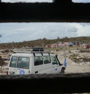 Dokters van de Wereld vrachtwagen staat geparkeerd in een verlaten landschap. Omgewaaide bomen, vernielde huizen en verdwaalde kleren: souvenirs van een orkaan die lelijk heeft huisgehouden. 