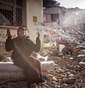 Biddende vrouw voor haar verwoeste huis in Defne (Hatay). ©Olivier Papegnies, 2023, Turkije.