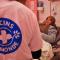 In een ziekenhuiskamer : op de voorgrond de rug van een verpleger die een T-shirt draagt met daarop het logo van Dokters van de Wereld. De verpleger staat aan het bed van een gesluierde vrouw die op een onderzoekstafel ligt. 